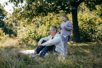 Adult father and little daughter are walking in the park