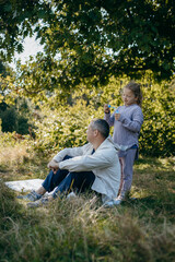 Adult father and little daughter are walking in the park