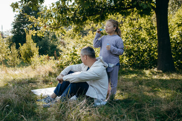 Adult father and little daughter are walking in the park