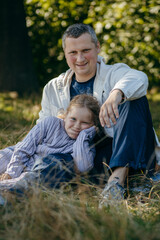 Adult father and little daughter are walking in the park