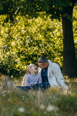 Adult father and little daughter are walking in the park