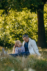 Adult father and little daughter are walking in the park