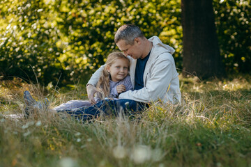 Adult father and little daughter are walking in the park