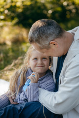 Adult father and little daughter are walking in the park