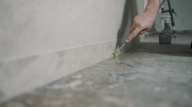 Worker applying grout to tile edges in home renovation project with precision tools for a seamless finish
