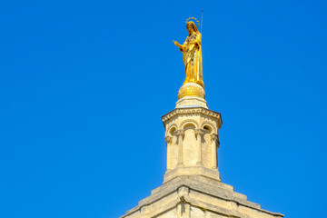 Palais des Papes (Palace of the Popes) in Avignon, France and a gilded statue of the Virgin Mary atop the cathedral tower. 
