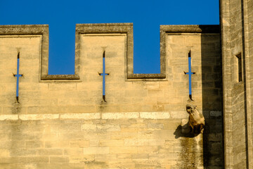 Gothic-style stone tower with a crenellated top and battlements with carved gargoyles in Avignon, France 