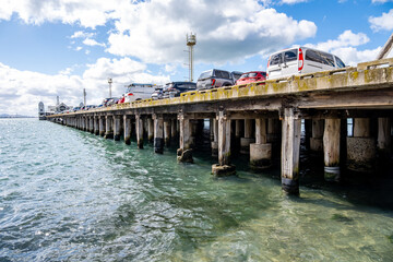 Obraz premium Cunningham Pier in Geelong, Victoria, Australia, with parked cars above wooden pylons over blue coastal waters. Concept of historic pier, maritime infrastructure, waterfront tourism