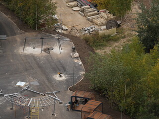 Playground construction site with swing set, wooden pergolas and building materials near trees
