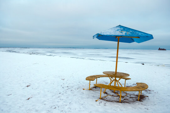 Winter beach with empty table and umbrella