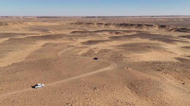 jeep car 4x4 driving around the Eye of the Sahara, also known as the Richat Structure in Mauritania, Sahara desert landscape aerial drone footage