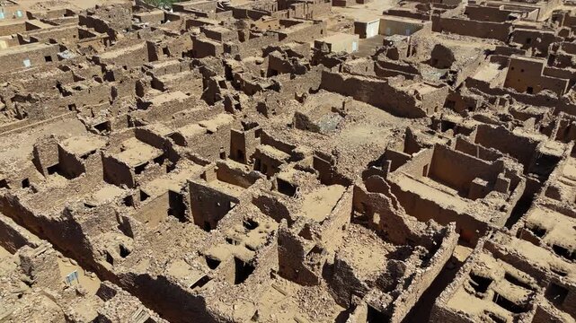 Drone aerial shot of the historic stone ruins and fortress of Ouadane in Mauritania, ancient desert town and UNESCO World Heritage site surrounded by Sahara sands