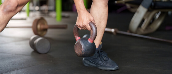 Fitness. Individual lifting kettlebell in gym setting.