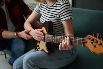 Obraz premium Tutor teaching woman to play guitar at home, closeup
