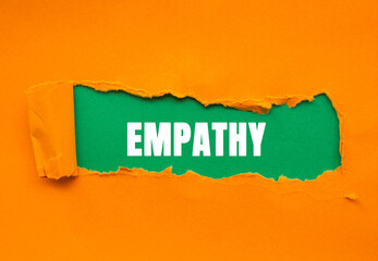 Empathy message written on ripped torn orange paper on green background. Conceptual Empathy symbol....