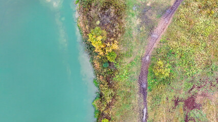 The shore of the reservoir is azure in color and the shore is covered with green vegetation. The road along the reservoir along the edge of the shore. High quality photo