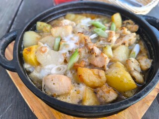 baked potatoes with chicken pieces and herbs in a frying pan