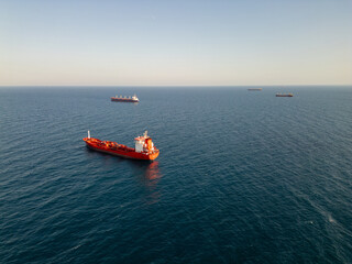 Aerial video of cargo ships anchored in calm open sea under clear sky. Peaceful maritime scene showcasing global trade and ocean transportation at sunrise or sunset