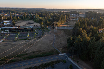 Aerial drone photo of Oregon City landscape at sunset featuring power lines, transmission towers, roads, buildings, forest areas, and open fields under warm autumn evening light