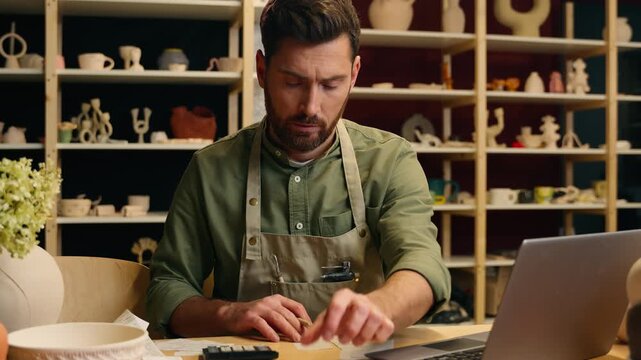 Upset serious desperate Caucasian man male guy small business owner potter craftsman businessman working managing finance budget counting taxes looking bill paper check receipt problems debt indoors