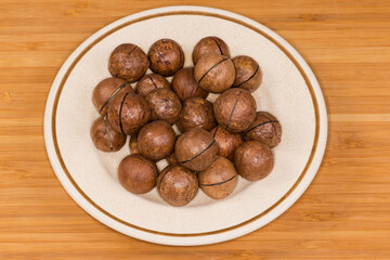 Whole macadamia nuts with sawn shells on a saucer