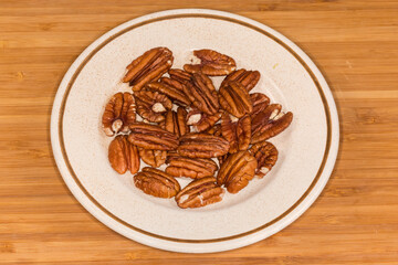 Peeled pecan nuts on saucer on a wooden surface