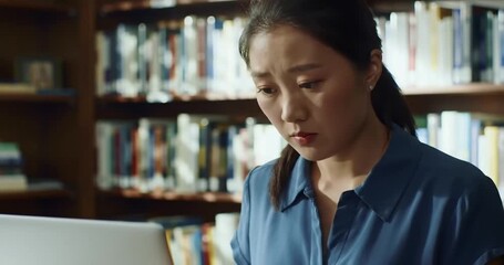 Focused woman studying in a library with books - Powered by Adobe