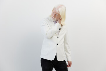 Businessman with long white hair in a stylish white blazer against a minimalistic white background...