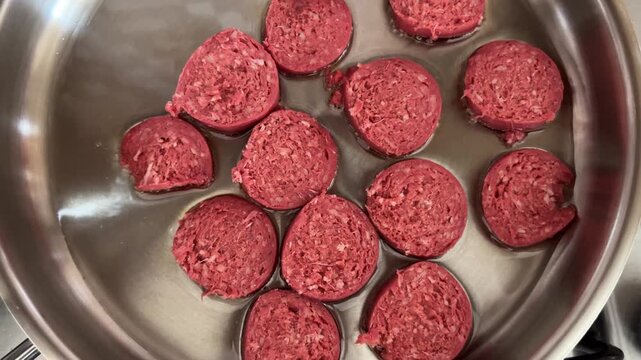 Raw slices of Turkish sucuk sausage cooking in sunflower oil pan