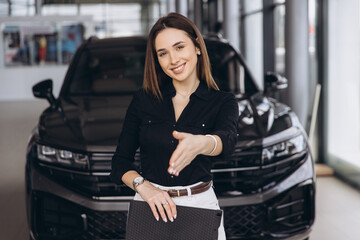 Woman extending hand for handshake in car dealership