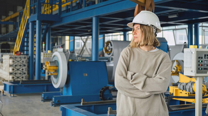 Industrial equipment for working with coil metal. Decoiler holds and unwinds metal coil. Slitting or cut-to-length line - cut coil metal into strips. Woman wearing helmet is working there