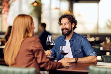Smiling Couple Sharing Wine at a Cozy Restaurant for a Romantic Evening