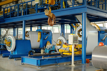 Industrial equipment for working with coil metal. Decoiler holds and unwinds metal coil. Slitting or cut-to-length line - cut coil metal into strips. Crane with hook - used for moving coils.