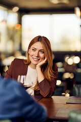 Smiling Woman Engaged in Conversation at a Casual Restaurant Setting