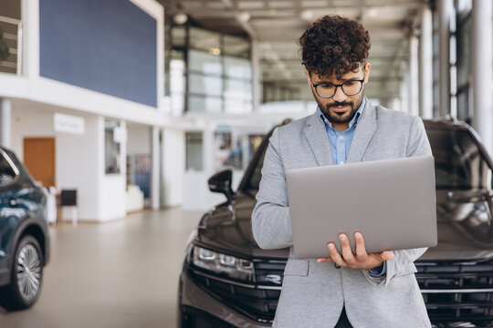 Arab businessman using laptop in car dealership