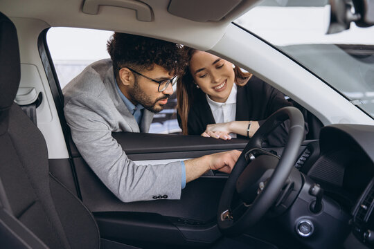 Multi ethnic couple buying car in dealership showroom
