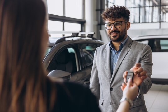 Car salesman handing over car key to customer