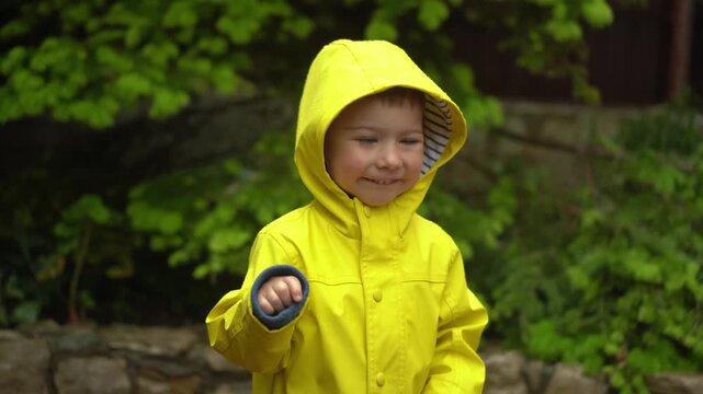 child in yellow raincoat with hood smiling