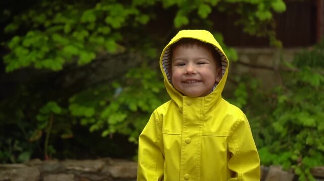 child in yellow raincoat with hood stands