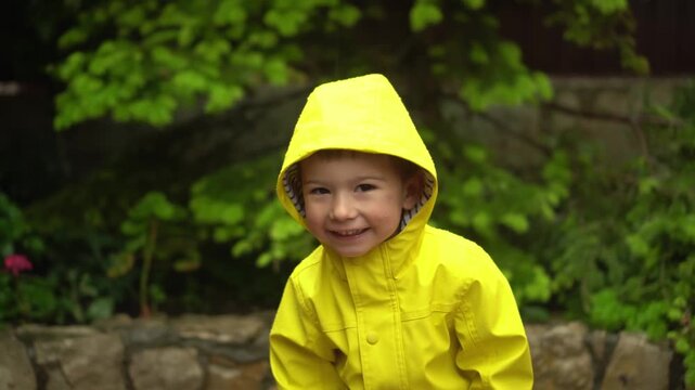 child in yellow raincoat with hood stands