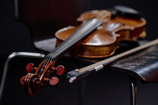 Close up showing classical wooden violin and bow resting on chair, highlighting fine craftsmanship and musical instrument details, suitable for music education or performance themes