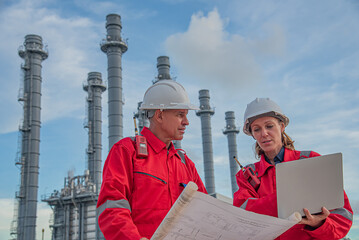Efficient teamwork in industrial setting with laptop and Industrial Plant or Refinery in the Background