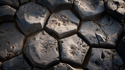 A close up shot of interlocking hexagonal basalt columns forming a natural rock formation surface