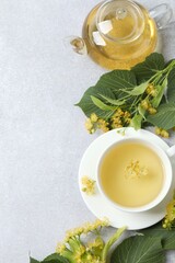 Green tea with fragrant linden in transparent cup on gray background