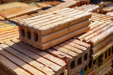 Pile of bricks for construction work, brown brick background, Close-up of stacked bricks ready to be used as a construction material.