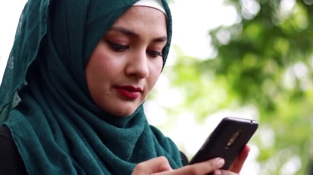 Close up panning shot of woman wearing hijab texting on cell phone