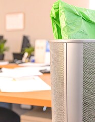 Office waste bin with green plastic bag