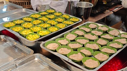 Thai pudding with coconut filled with taro and corn, in a banana cup.