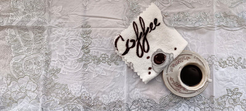A small cup of coffee on a saucer with a napkin are on the table, top veiw