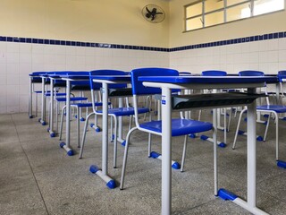Naklejka premium Cadeiras e mesas de uma sala de aula vazia em uma escola pública.
